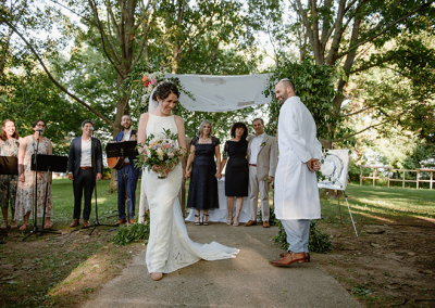 Photo of a bride and groom standing near the chuppah at their wedding